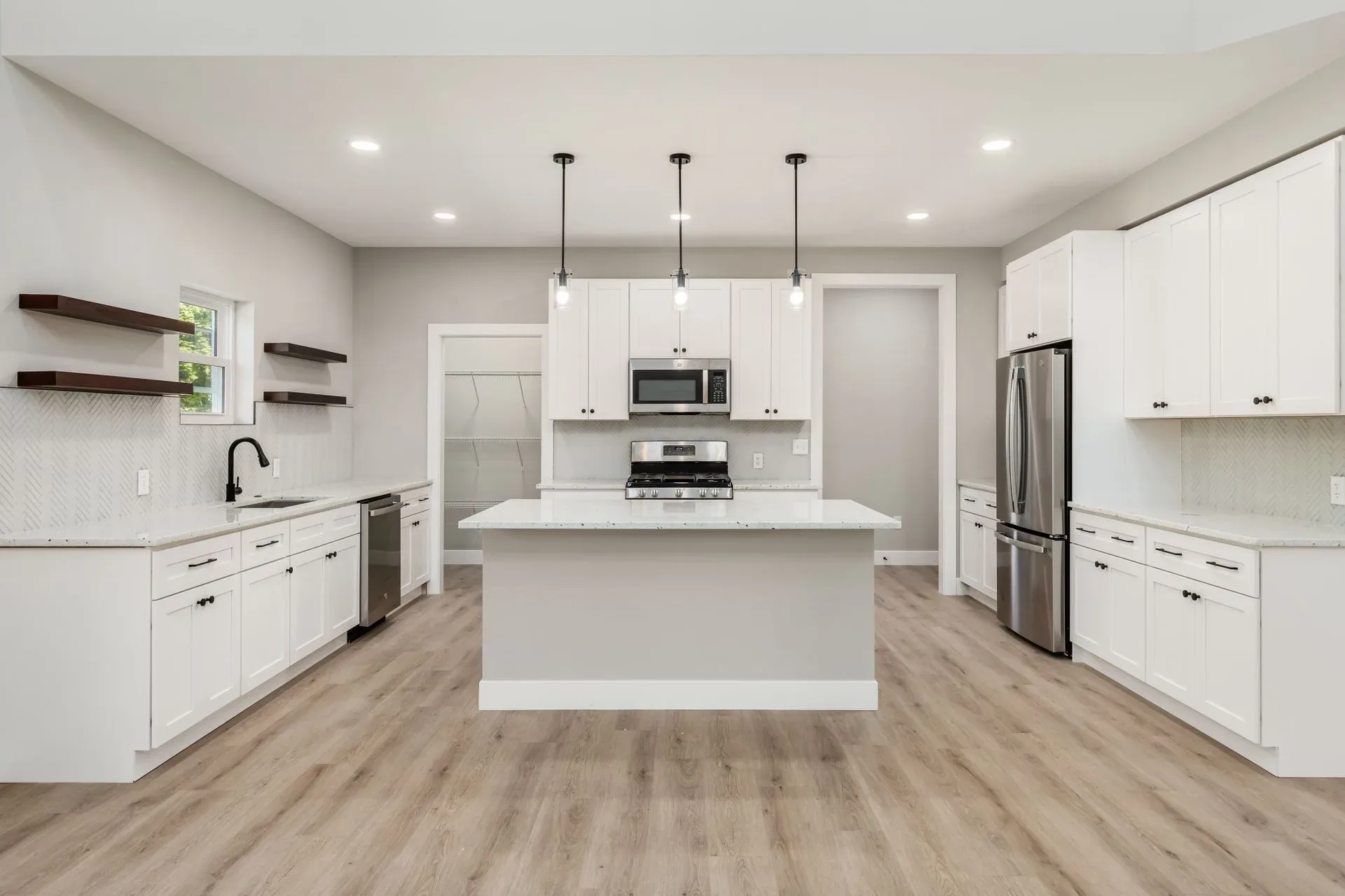 A white kitchen with hardwood floors and stainless steel appliances.